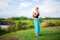 Outdoor yoga practice. Young woman standing on the grass. Hands in namaste mudra, closed eyes. Tanah Lot temple, Bali Royalty Free Stock Photo