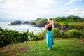 Outdoor yoga practice. Young woman standing on the grass. Hands in namaste mudra, closed eyes. Tanah Lot temple, Bali Royalty Free Stock Photo