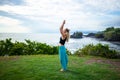 Outdoor yoga practice. Young woman standing on the grass. Hands raising up in namaste mudra, closed eyes. Tanah Lot temple, Bali Royalty Free Stock Photo