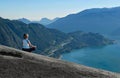 Outdoor yoga retreat. Woman in lotus pose meditating on mountain top with beautiful views.