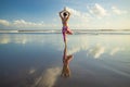 Outdoor yoga. Vrikshasana asana. Slim woman practicing tree pose on the beach. Water reflection. Perfect balance. Yoga retreat.