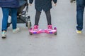 Young girl riding a hoverboard scooter in the park, family concept, woman with stroller, outdoor activity