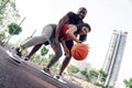 Outdoors Activity. African couple on basketball court girl dribbling while guy hugging blocking her happy bottom view Royalty Free Stock Photo