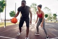 Outdoors Activity. African couple guy dribbling concentrated while girl defencing backdoor happy on basketball court Royalty Free Stock Photo