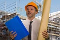 Corporate portrait of young attractive and successful engineer man or architect working on building at construction site wearing Royalty Free Stock Photo