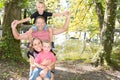 Outdoors family of four piggyback with mother father and two brother son in summer garden