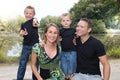 Outdoors family portrait of happy group of four in green summer park pond aside lake river