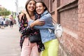 Outdoors fashion portrait young pretty best girls friends in friendly hug. Walking at the city.