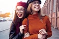 Outdoors fashion portrait young pretty best girls friends in friendly hug. Walking at the city. Posing at the street