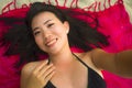 Outdoors fresh and natural portrait of young beautiful and happy Asian Korean woman in bikini lying flat on sarong on beach sand Royalty Free Stock Photo