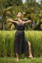 Outdoors holidays portrait of middle aged attractive and elegant Asian woman in black dress enjoying beauty of nature at tropical