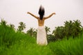 Outdoors holidays - rear view of young attractive and elegant woman in white dress opening arms free enjoying beauty of nature at