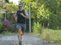 Outdoors jogging workout - young attractive and happy man in sport clothes and sunglasses running in city park enjoying fitness in Royalty Free Stock Photo