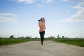 Outdoors jogging workout - young happy and dedicated Asian Chinese woman running at beautiful ccountryside road under a blue sky Royalty Free Stock Photo