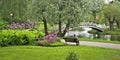 Outdoors landscape of a park with a pond, flowers, bench and bridge Royalty Free Stock Photo