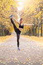 Outdoors leisure. Girl in sportswear standing in the autumn park doing pirouette smiling cheerful balancing full body