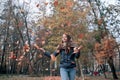 Outdoors lifestyle fashion image of happy beautiful girl throwing leaves up in the air in autumn park Royalty Free Stock Photo