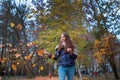 Outdoors lifestyle fashion image of happy beautiful girl throwing leaves up in the air in autumn park Royalty Free Stock Photo