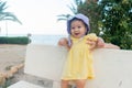 outdoors lifestyle portrait of adorable and happy baby girl in cute hat hold by her mothers hands on park bench looking excited Royalty Free Stock Photo