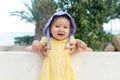 outdoors lifestyle portrait of adorable and happy baby girl in cute hat hold by her mothers hands on park bench looking excited Royalty Free Stock Photo