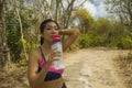 Outdoors lifestyle portrait of young attractive tired and thirsty Asian woman drinking water after hard running workout cooling Royalty Free Stock Photo