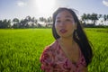 Outdoors lifestyle portrait of young beautiful and happy Asian Korean woman enjoying walk at green rice field under blue sky on a Royalty Free Stock Photo