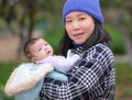 Outdoors lifestyle portrait of young happy and beautiful Asian Chinese woman as mother of little adorable baby girl holding her Royalty Free Stock Photo