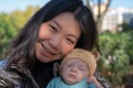 Outdoors lifestyle portrait of young happy and beautiful Asian Chinese woman as mother of little adorable baby girl holding her Royalty Free Stock Photo