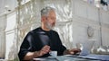 Outdoors man working computer closeup. Stylish senior drinking coffee in cafe Royalty Free Stock Photo