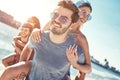 Outdoors photo of happy boyfriends piggybacking their girlfriends at sunset on beach Royalty Free Stock Photo