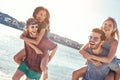 Outdoors photo of happy boyfriends piggybacking their girlfriends at sunset on beach Royalty Free Stock Photo