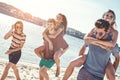 Outdoors photo of happy boyfriends piggybacking their girlfriends at sunset on beach Royalty Free Stock Photo