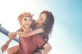 Outdoors photo of happy boyfriends piggybacking their girlfriends at sunset on beach Royalty Free Stock Photo