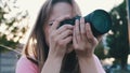 Outdoors photoshoot. Female photographer looking through the viewfinder of her dslr camera