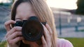 Outdoors photoshoot. Female photographer looking through the viewfinder of her dslr camera