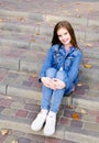 Outdoors portrait of adorable smiling little girl child sitting on the steps of the stairs