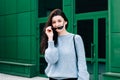 Outdoors portrait of beautiful young brunette girl. Teenage glamour girl with sunglasses wearing trendy outfit posing in city Royalty Free Stock Photo