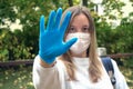 Outdoors portrait of beautiful young woman wearing cotton white mask and medicalgloves greeting and say hello, Nature and trees in