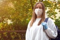 Outdoors portrait of beautiful young woman wearing cotton white mask and medicalgloves greeting and say hello, Nature and trees in