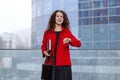 Horizontal portrait of a cheerful business woman, in red suit, coming on a job, look at the time. Business content.