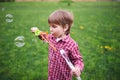 Outdoors portrait of cute preschool boy blowing soap bubbles on a green lawn at the playground Royalty Free Stock Photo