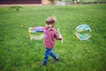 Outdoors portrait of cute preschool boy blowing soap bubbles on a green lawn at the playground Royalty Free Stock Photo