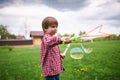 Outdoors portrait of cute preschool boy blowing soap bubbles on a green lawn at the playground Royalty Free Stock Photo