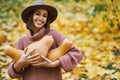 Outdoors portrait delighted woman in hat embracing big pumpkins surrounded orange leaves