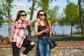 Outdoors portrait of female friends drinking coffee and having fun. Background nature, park, river. Urban lifestyle and friendship Royalty Free Stock Photo