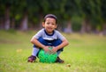 Outdoors portrait at grass city park of 5 years old Asian Indonesian child smiling happy and cheerful sitting on ball laughing