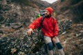 Outdoors portrait of tired hiker man in red clothes sitting on the rock relaxing after hiking in mountain. Royalty Free Stock Photo