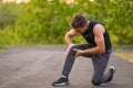 Outdoors portrait of young attractive sport man in pain touching his knee suffering ligaments accident or some injury during Royalty Free Stock Photo