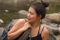 Outdoors portrait of young beautiful and happy Asian Japanese woman carrying backpack trekking on mountains crossing river Royalty Free Stock Photo