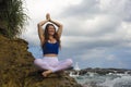 Outdoors portrait of young beautiful and happy red hair woman practicing yoga and meditation exercise in lotus position at beach Royalty Free Stock Photo